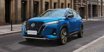 Nissan Kicks Azul andando em uma rua da cidade.