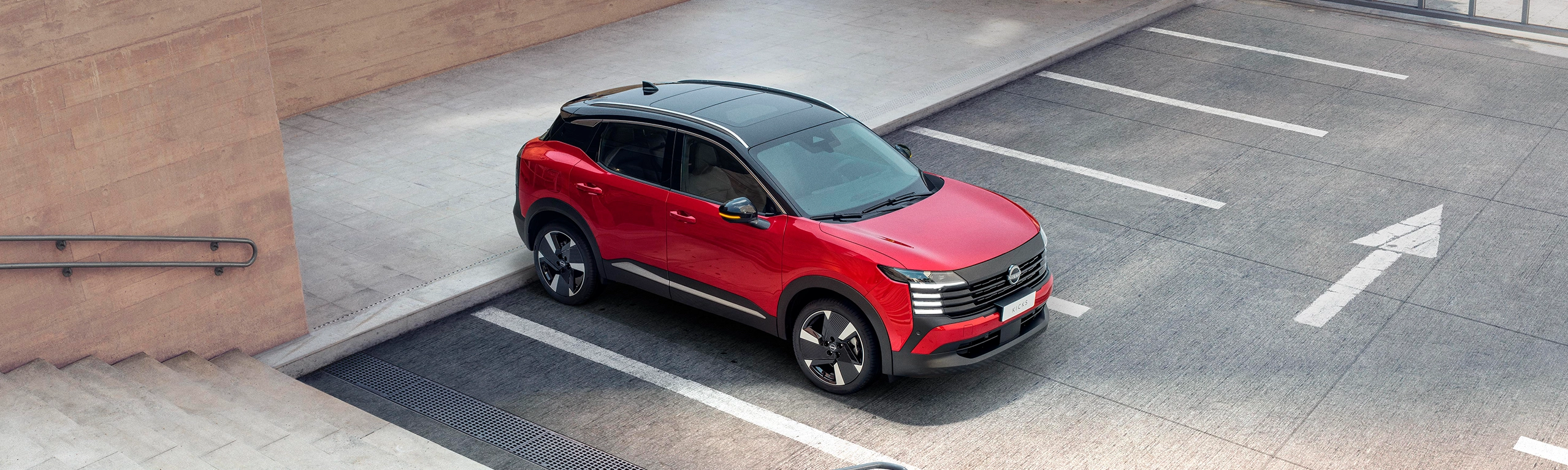 SUV Nissan Kicks vermelho com teto preto, visto de cima em ângulo diagonal.