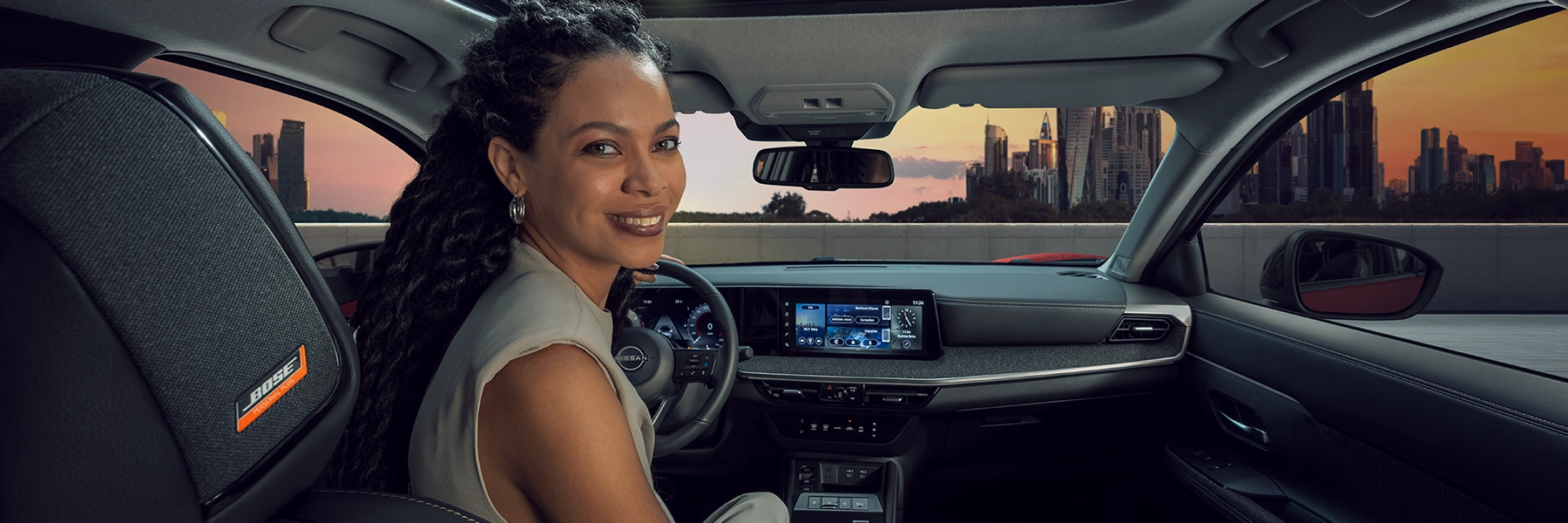 Motorista no interior de veículo Nissan com foco no painel digital e central multimídia.