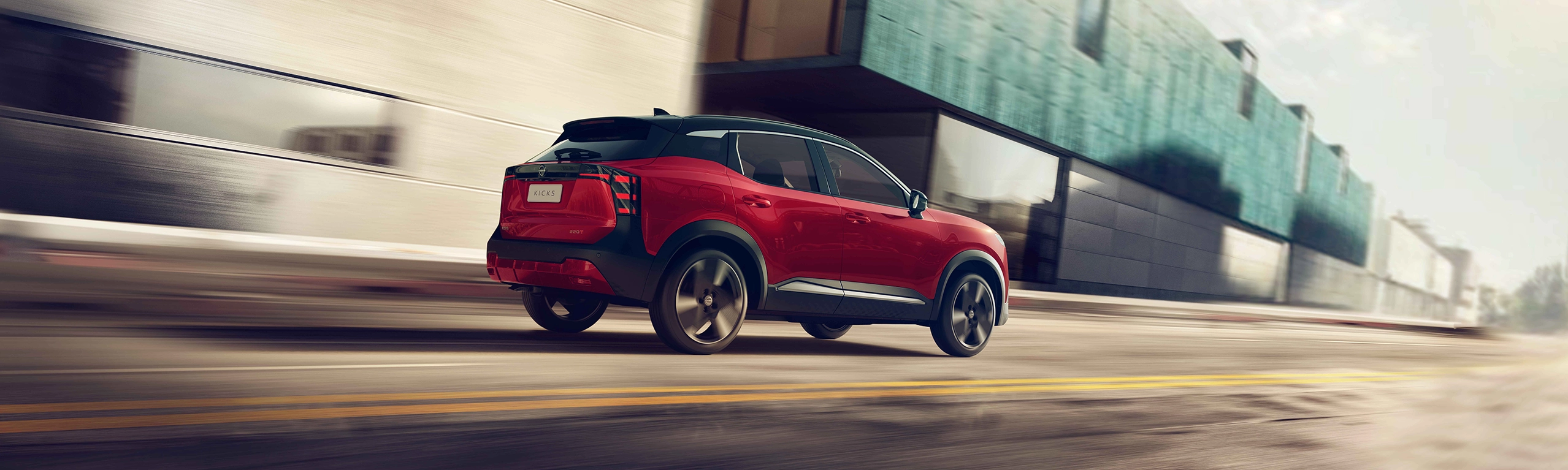 Nissan Kicks vermelho com teto preto em movimento por uma rua urbana, visto pelo ângulo traseiro direito com efeito de desfoque para indicar velocidade.