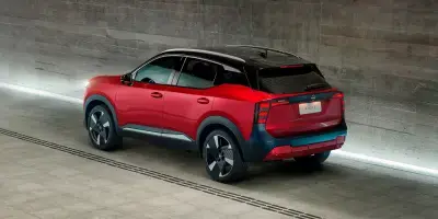 SUV Nissan Kicks vermelho com teto preto visto de trás em um túnel de concreto moderno e iluminado.