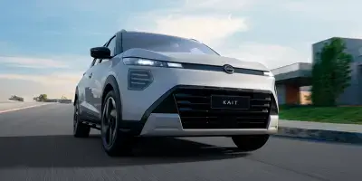 Homem de camisa vermelha segurando o volante de um carro em movimento, com um borrão de velocidade vermelho e branco visível fora da janela.