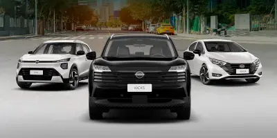 Três carros alinhados de frente em uma rua: Nissan Kicks preto ao centro, ladeado por dois modelos brancos.
