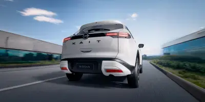 Traseira de um SUV Kait Nissan branco estacionado na entrada de uma casa de arquitetura moderna, com destaque para o design das lanternas.