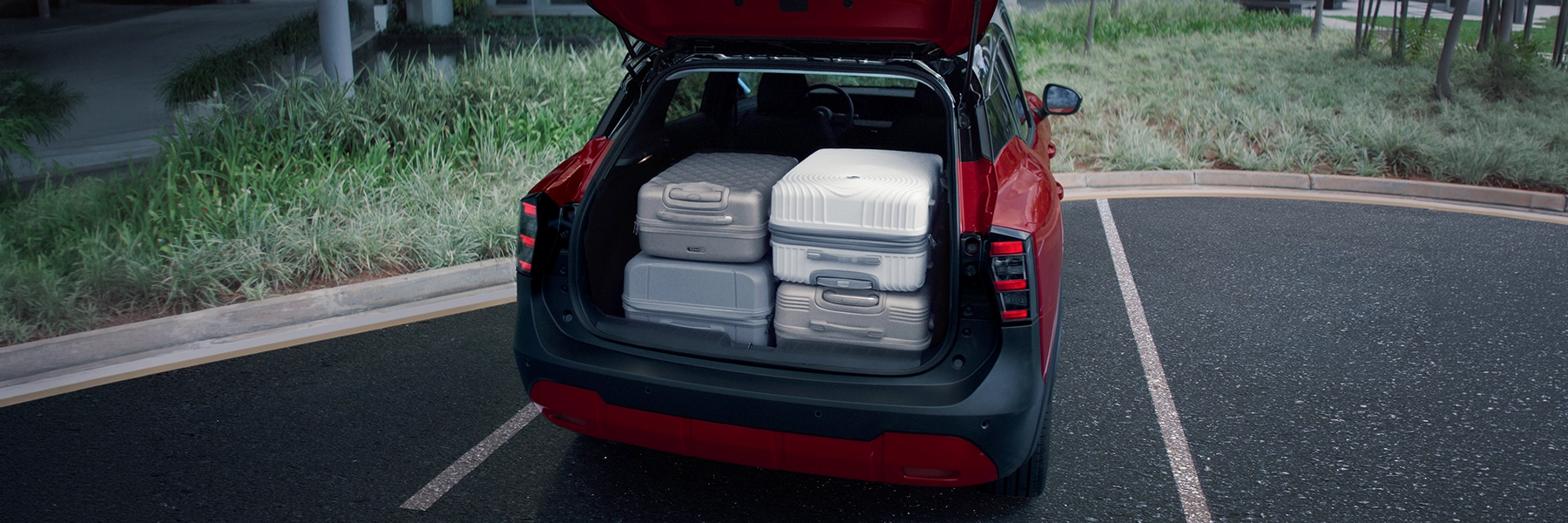 Porta-malas aberto de SUV vermelho com quatro malas de viagem acomodadas, demonstrando a capacidade de carga.