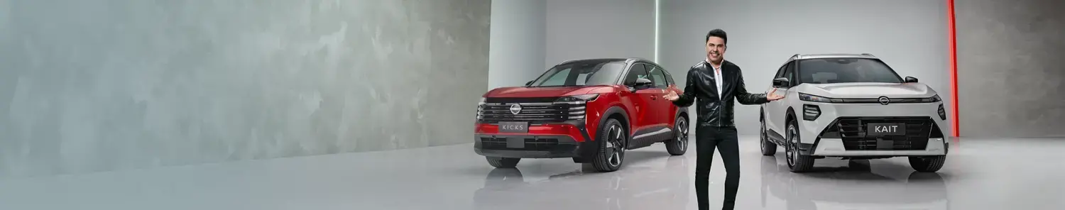 Banner publicitário com o cantor Zezé Di Camargo no centro, de braços abertos, apresentando dois SUVs Nissan Kicks em um estúdio moderno: um vermelho à esquerda e um branco à direita com a placa "KAIT".