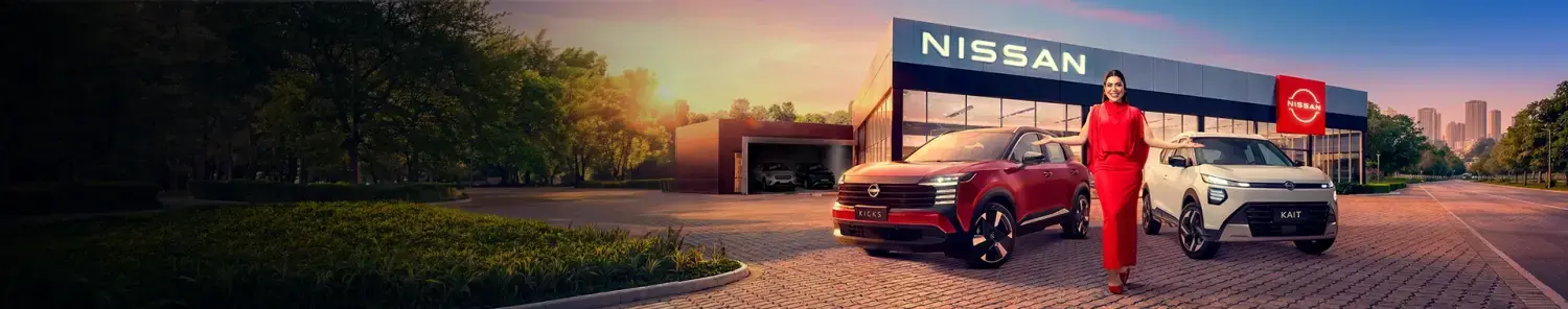 Banner de concessionária Nissan ao pôr do sol. Uma mulher de vestido vermelho está de braços abertos entre um Nissan Kicks vermelho e um Nissan Kait branco, em frente à fachada iluminada da loja.