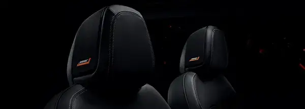 Detalhe do encosto de cabeça (headrest) dos bancos em couro preto do Nissan. O logo BOSE laranja e branco, indicando sistema de áudio integrado, é visível.