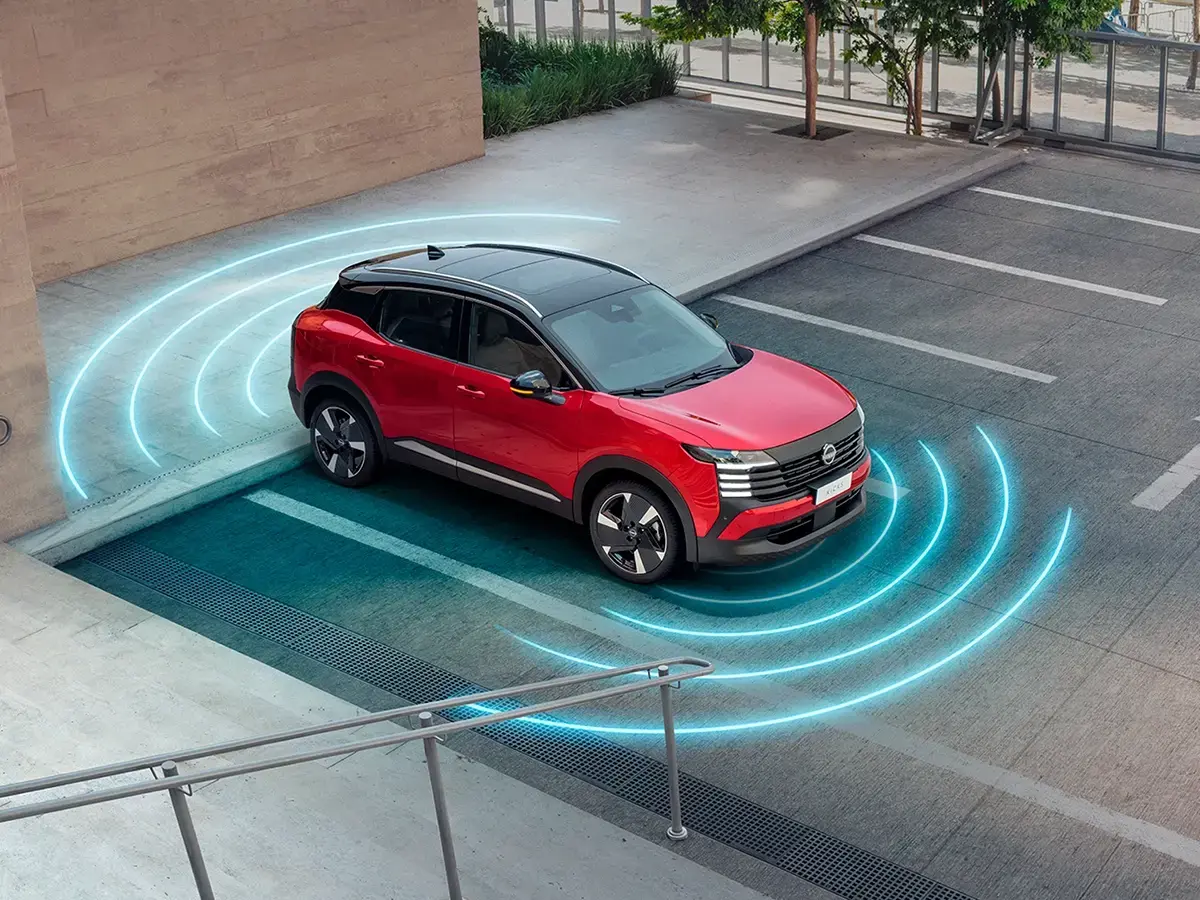 Nissan Kicks vermelho estacionado perto de uma rampa, com anéis azuis luminosos ao redor do carro, visualizando a ativação de um sensor ou sistema de segurança.
