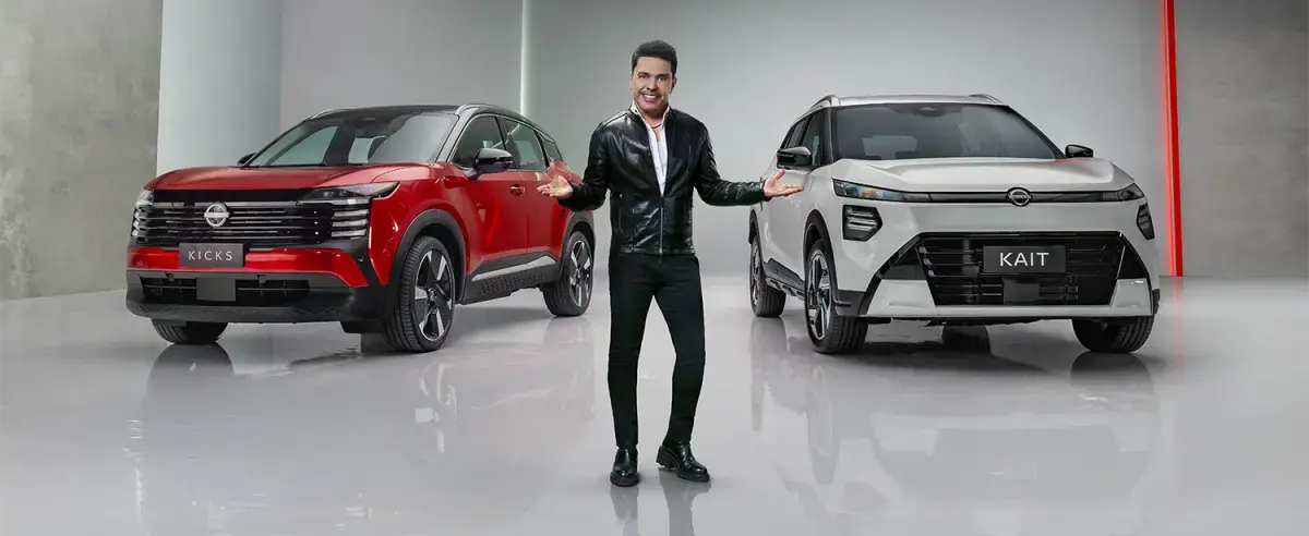 Banner publicitário com o cantor Zezé Di Camargo no centro, de braços abertos, apresentando dois SUVs Nissan Kicks em um estúdio moderno: um vermelho à esquerda e um branco à direita com a placa "KAIT".