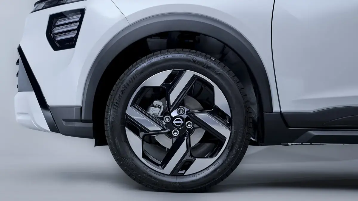 Close-up da roda de liga leve preta e prata do Nissan KAIT. Vista lateral baixa.