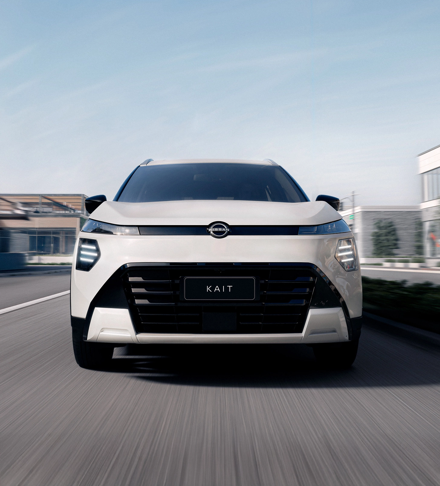 SUV Nissan KAIT branco visto de frente em movimento rápido em uma rua urbana. O fundo da cidade está borrado, indicando velocidade.