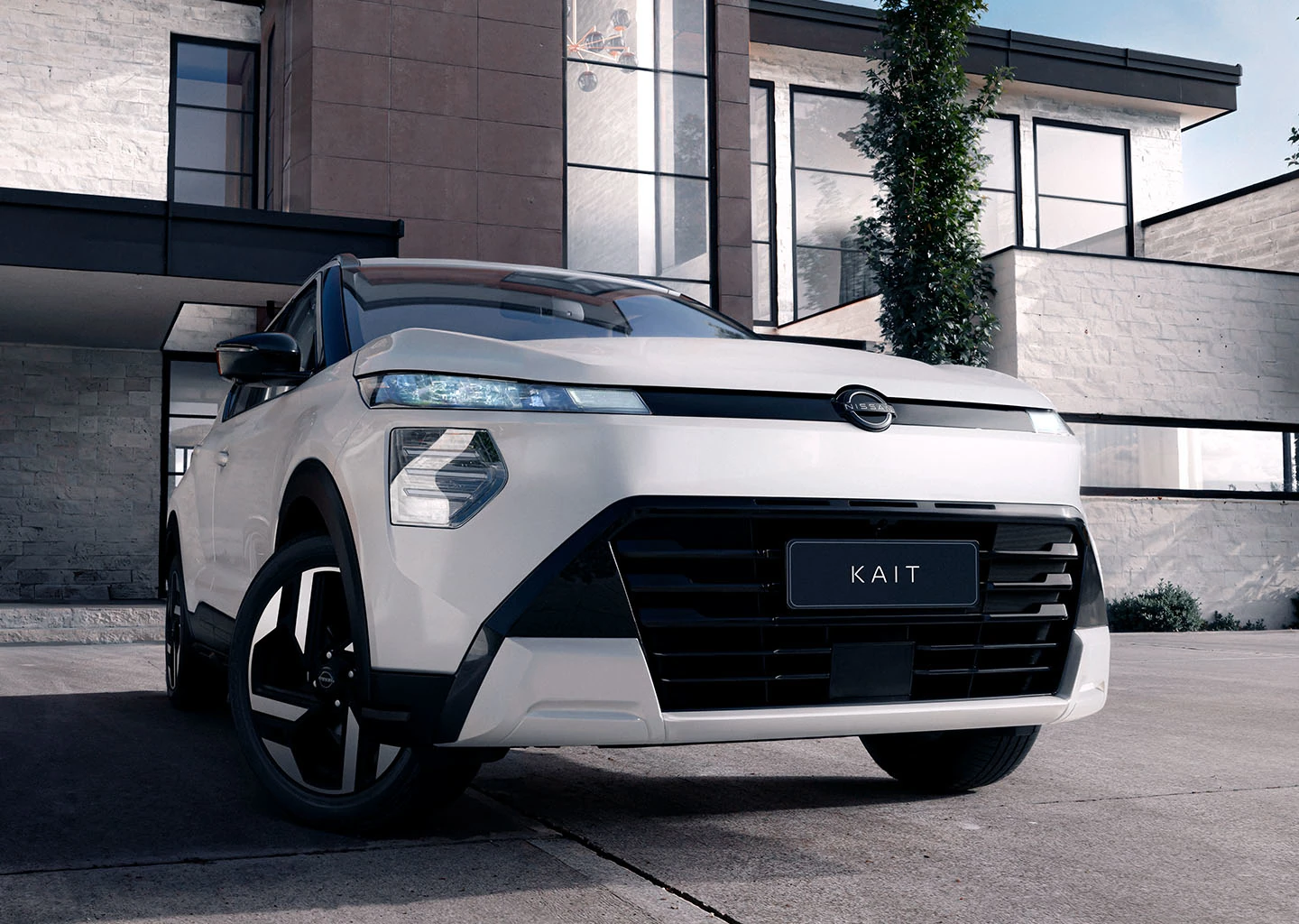 Vista frontal de baixo de um SUV Nissan KAIT branco estacionado em frente a uma residência moderna com diferentes texturas. O design frontal angular e as luzes são destacados.