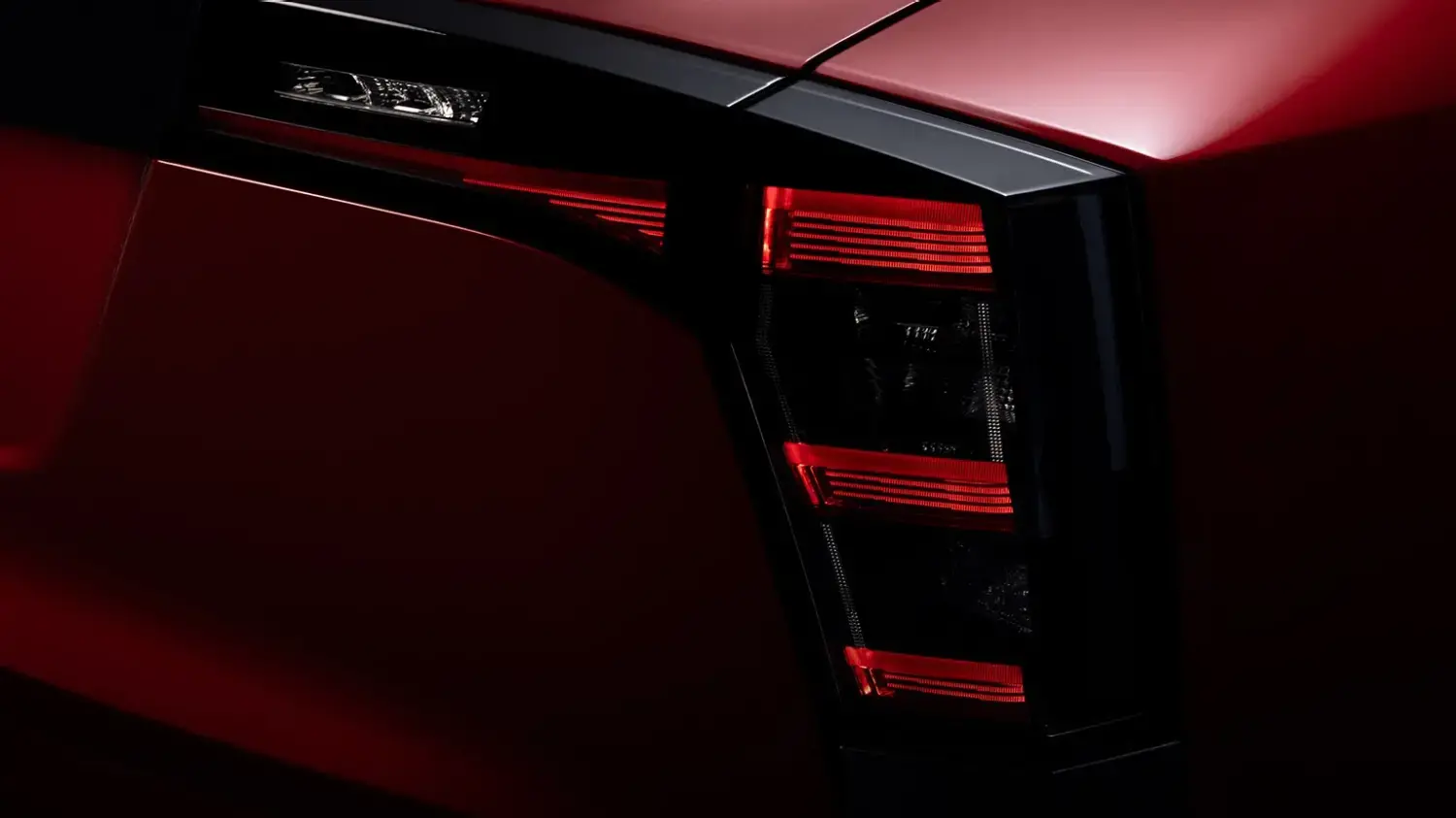 Close-up detalhado da lanterna traseira vertical do Nissan Kicks vermelho, exibindo um intrincado padrão de iluminação LED. O design angular e moderno da luz traseira reflete a inovação no estilo do SUV.