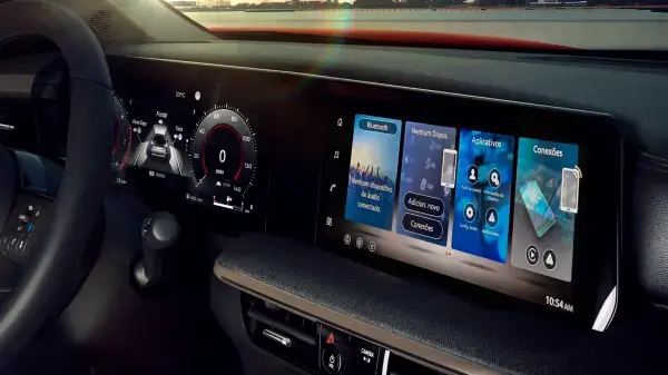 Painel digital duplo do Nissan Kicks, mostrando a tela do painel de instrumentos à esquerda com velocímetro e informações de direção, e a tela de multimídia à direita exibindo a interface do Apple CarPlay com opções de música, chamadas e um relógio digital. O interior do carro reflete a luz do pôr do sol.