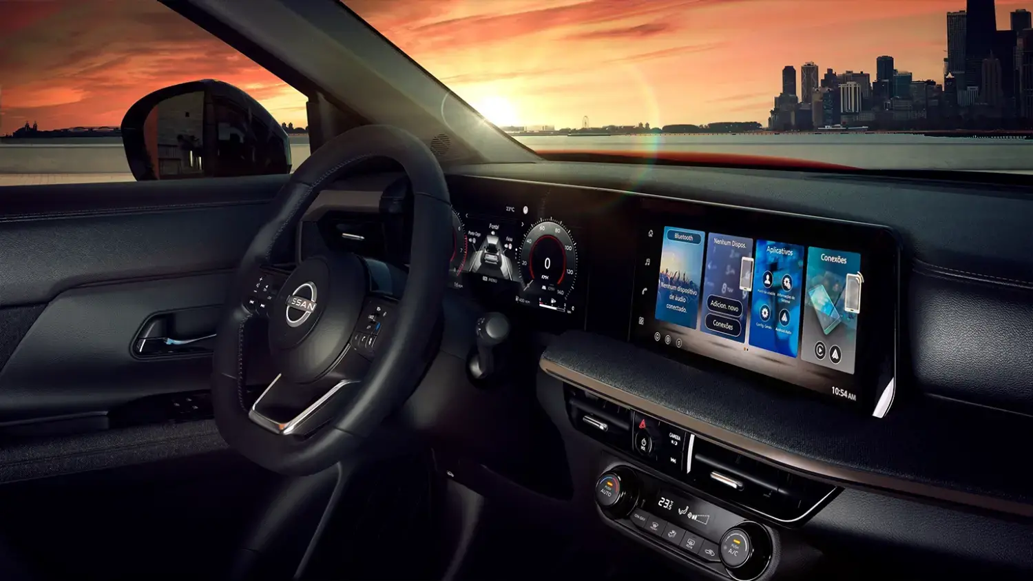 Vista interna do painel de um Nissan Kicks, com o volante multifuncional e as telas digitais acesas, exibindo o logotipo Nissan na tela central. O para-brisa mostra uma paisagem urbana com um pôr do sol alaranjado, refletindo a iluminação interna.