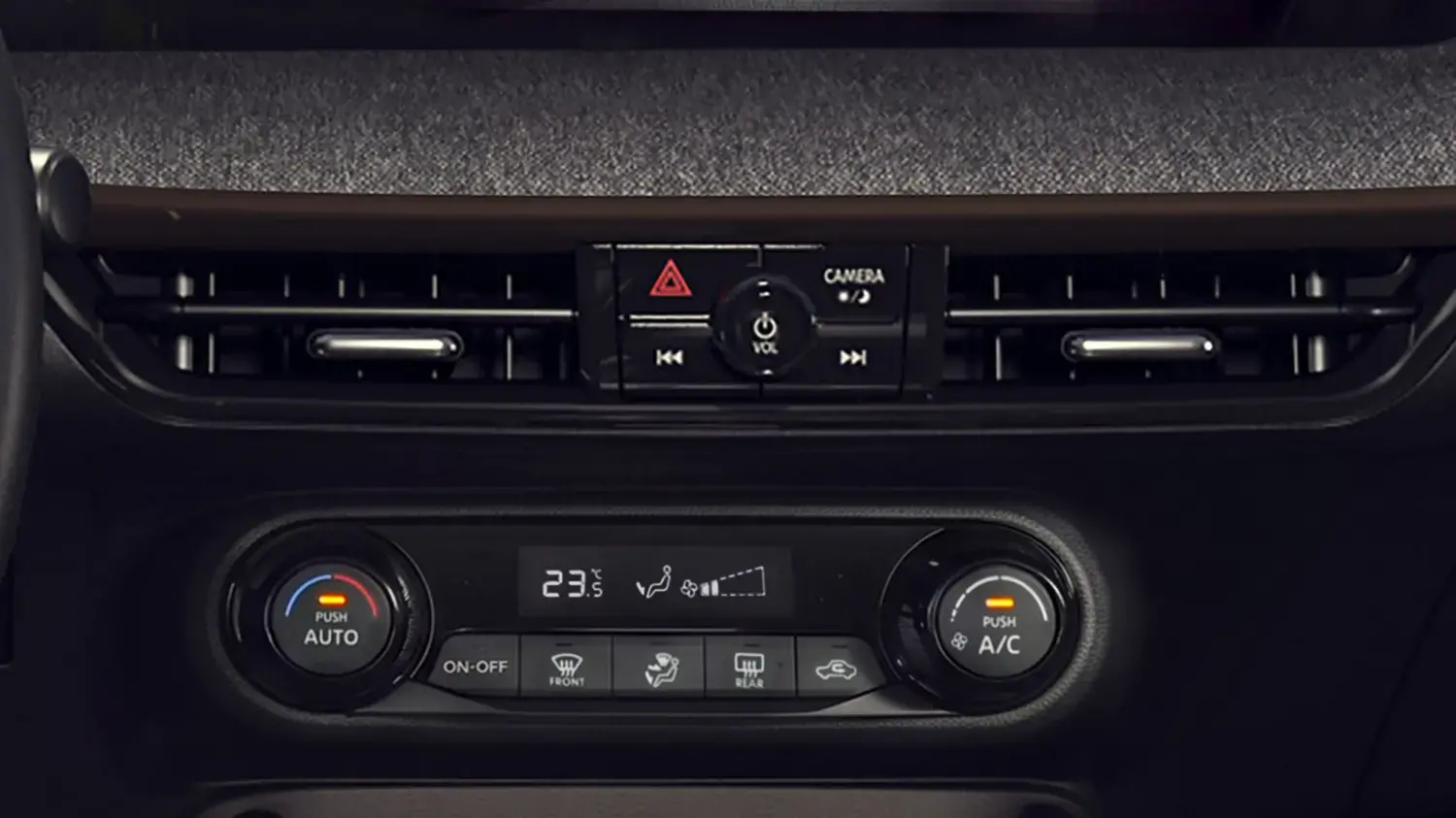 Close-up dos controles digitais de climatização de um Nissan Kicks. Várias saídas de ar horizontais estão acima de uma fileira de botões sensíveis ao toque para funções como desembaçador e modo automático, e um botão giratório central.