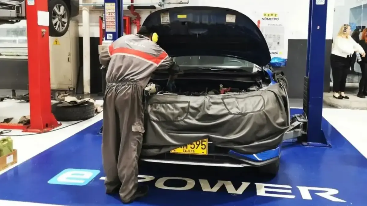 Técnico de Nissan revisa el motor de un vehículo e-POWER con el capó abierto en un taller de posventa