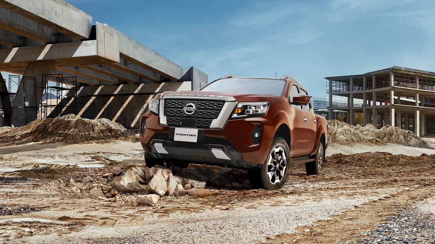 2021 Nissan Frontier on the beach with person unloading surfboard from truck bed