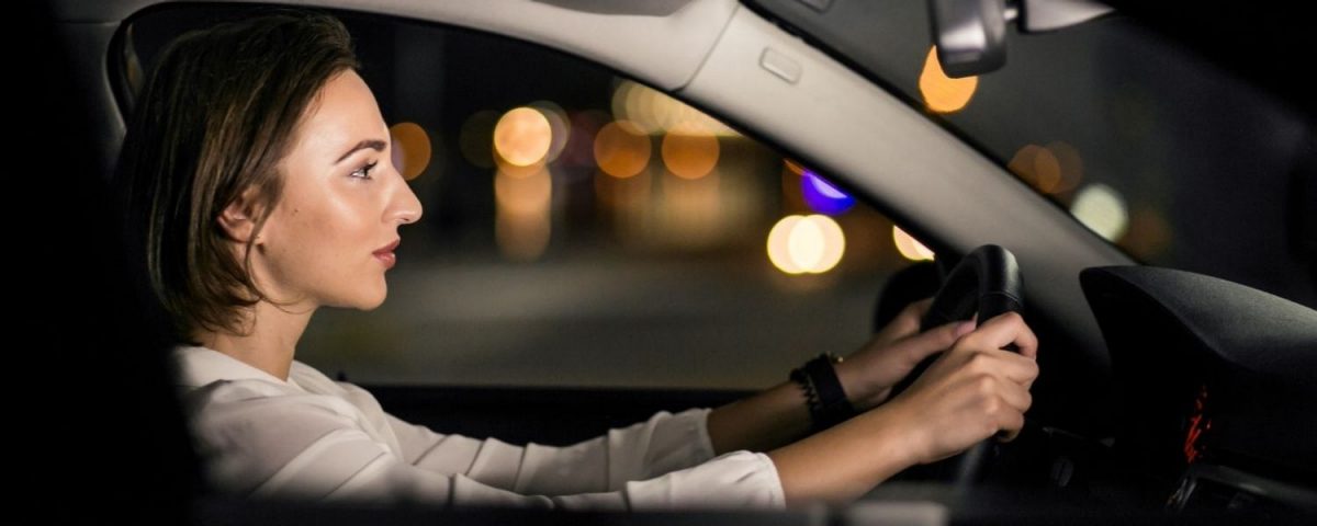 Mujer manejando un vehículo de noche